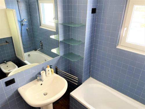 een blauw betegelde badkamer met een wastafel en een bad bij Attico Paderno Dugnano - Milano in Paderno Dugnano