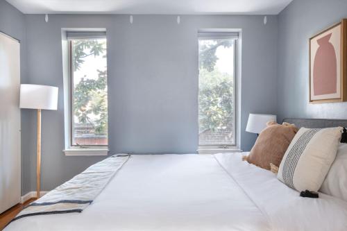 a large bed in a bedroom with two windows at Georgetown 2br w wd nr Embassy Row nightlife WDC-705 in Washington, D.C.