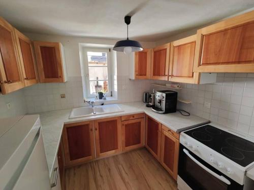 une cuisine avec des armoires en bois et un évier dans l'établissement Maison au cœur des vignobles, à Westhoffen