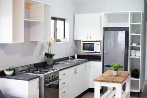 Kingsborough的住宿－90 Eden Sands 2 Bedroom Flat with Beach Access，厨房配有白色橱柜、炉灶和桌子。