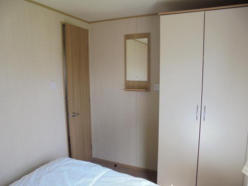 a bedroom with a bed and a mirror and a closet at Kingfisher : Horizon II:- 8 Berth, Close to site entrance in Ingoldmells