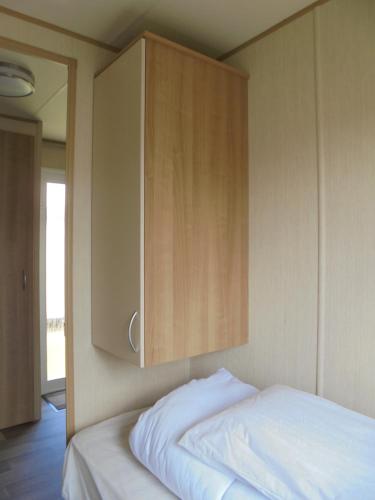 a bedroom with a bed with a wooden cabinet at Kingfisher : Horizon II:- 8 Berth, Close to site entrance in Ingoldmells