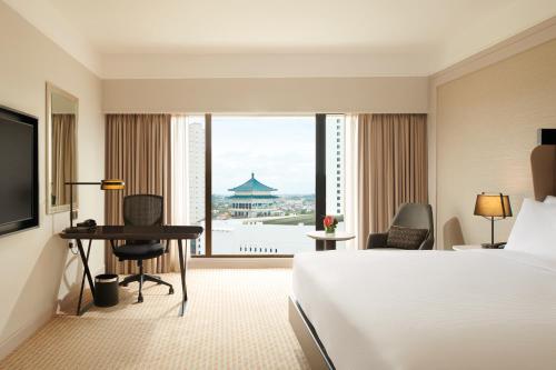a hotel room with a bed and a large window at Hilton Kuching Hotel in Kuching