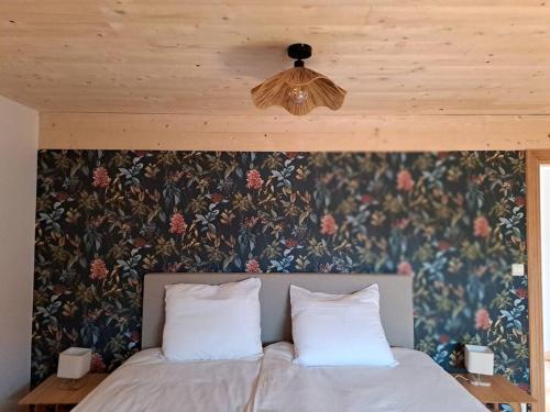 1 cama con 2 almohadas blancas y una pared con flores en Maison Patisson, en Kasterlee
