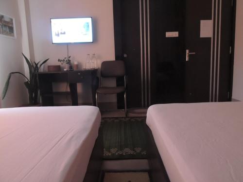 a hotel room with two beds and a tv at Sublime Homestay in Bhubaneshwar