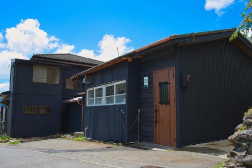a black house with a brown door in a driveway at root hakone in Hakone