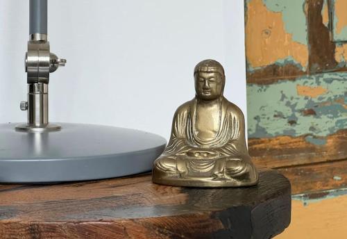 una statua di Buddha in ottone seduta su un tavolo accanto a un lavandino di The Wimberry a Blackwater