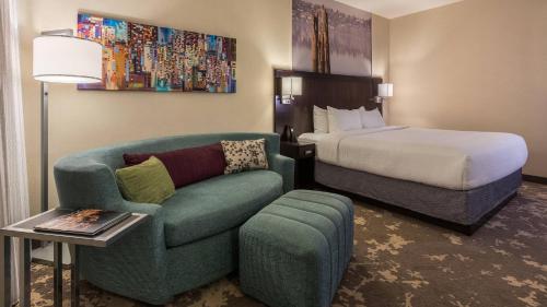 ポートランドにあるCourtyard by Marriott Portland City Centerのベッド、ソファ、椅子が備わるホテルルームです。