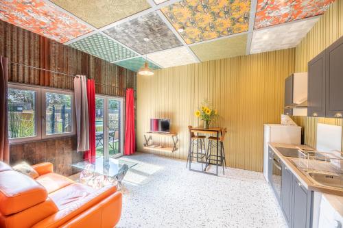 sala de estar con sofá naranja y cocina en La Maison du Bois Brûlé 2 - Avec piscine partagée, en Villaines-les-Rochers