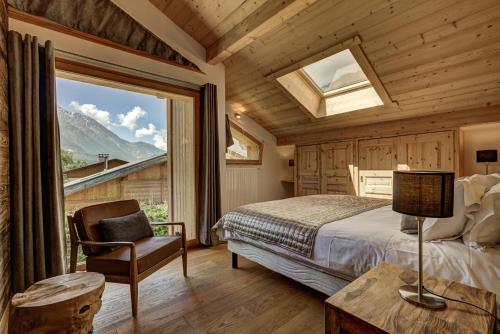 een slaapkamer met een bed, een stoel en een raam bij Chalet Planards 2 in Chamonix-Mont-Blanc