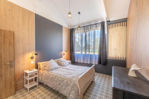 ein Schlafzimmer mit einem Bett und einem großen Fenster in der Unterkunft La Maison du Bois Brûlé 1 - Avec piscine partagée in Villaines-les-Rochers