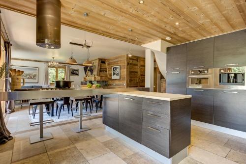 une cuisine avec un grand îlot et des tabourets de bar dans l'établissement Chalet Sanaz, à Chamonix-Mont-Blanc