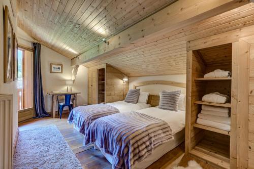 deux lits dans une chambre aux murs en bois dans l'établissement Chalet Sanaz, à Chamonix-Mont-Blanc