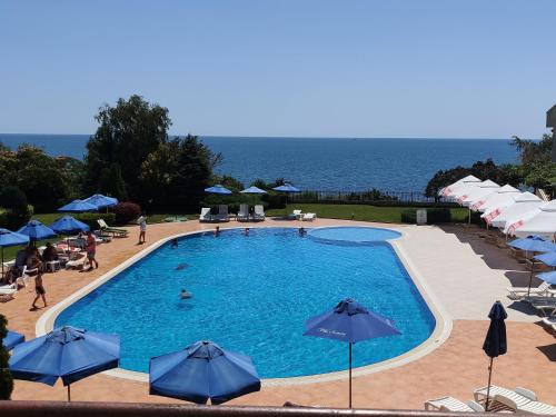 a swimming pool with umbrellas and the ocean in the background at SUN AND FLOWERS APARTMENTS in front of the sea in Topola