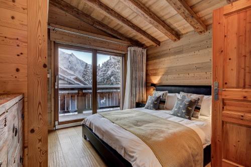 une chambre avec un lit et une grande fenêtre dans l'établissement Chalet Capricorne, à Chamonix-Mont-Blanc