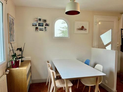 une salle à manger avec une table et des chaises blanches dans l'établissement Maison au calme à Dirinon, à Dirinon