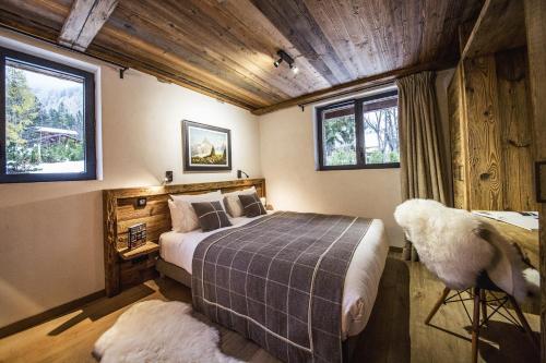 a bedroom with a bed and a desk and windows at Chalet Black Wood in Chamonix-Mont-Blanc