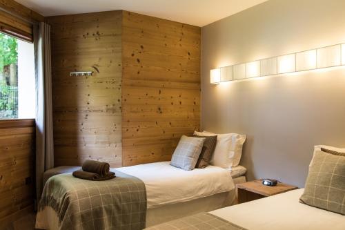 2 letti in una camera con pareti in legno di Villa Floria Apartment a Chamonix-Mont-Blanc