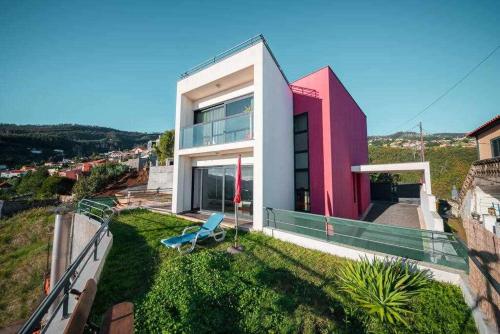 a red and white house with a blue chair on the grass at Casa da Terça - Nice View and Parking in Funchal