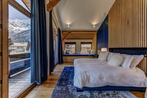 une chambre avec un lit et une grande fenêtre dans l'établissement Chalet Trois Soeurs, à Chamonix-Mont-Blanc