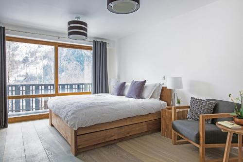 ein Schlafzimmer mit einem Bett, einem Stuhl und einem Fenster in der Unterkunft Le Brevent 3 Apartment in Chamonix-Mont-Blanc