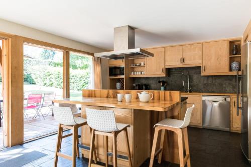 une cuisine avec des armoires en bois et un îlot avec des tabourets de bar dans l'établissement Chalet Les Favrands, à Chamonix-Mont-Blanc