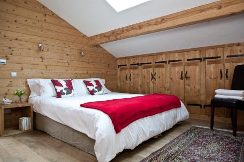 - une chambre avec des murs en bois et un lit avec une couverture rouge dans l'établissement Chalet Les Favrands, à Chamonix-Mont-Blanc