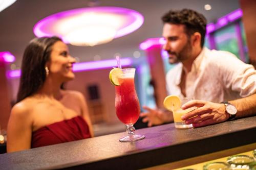 a man and a woman sitting at a bar with a drink at Das Schloss an der Eisenstrasse in Waidhofen an der Ybbs