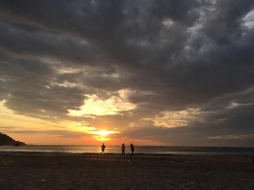 three people walking on the beach at sunset at Cá Mặn Homestay in Quy Nhon