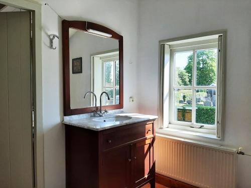 baño con lavabo, espejo y ventana en Gastenverblijf De Loft, en Warns