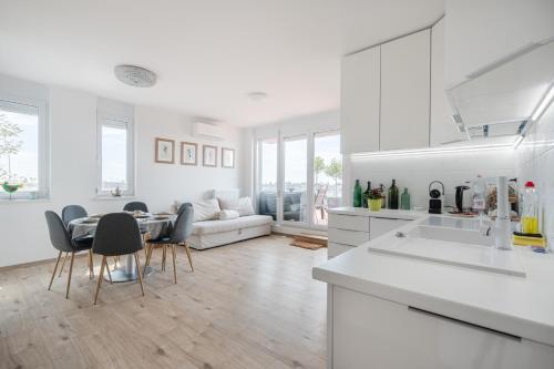 una cucina bianca e un soggiorno con tavolo e sedie di Sunset Towers Apartment a Budapest