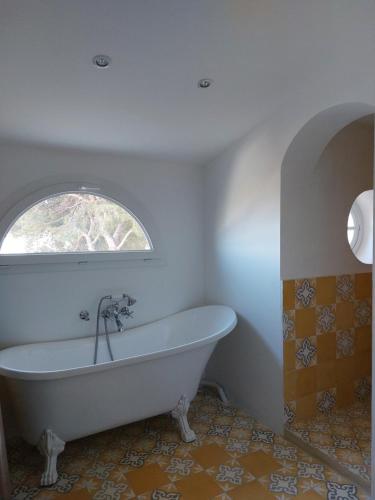 La salle de bains est pourvue d'une baignoire blanche et d'une fenêtre. dans l'établissement Casa des Pins - Villa d’exception à Sète, à Sète
