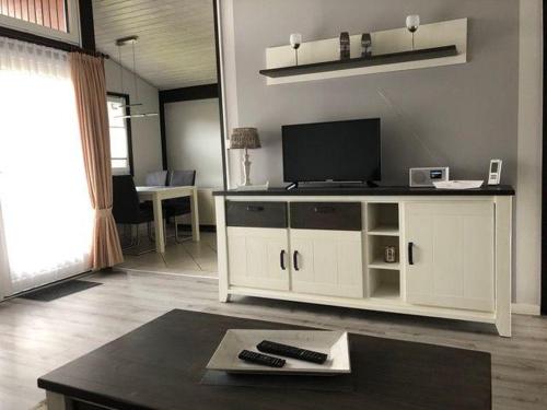 a living room with a white entertainment center with a flat screen tv at Ferienpark Fedderwardersiel in Fedderwarderdeich