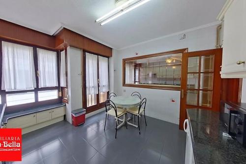 a dining room with a table and chairs and windows at Amplio y céntrico piso en Santoña in Santoña