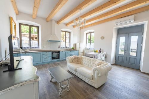 a living room with a couch and a kitchen with blue cabinets at Amalija Apartments in Strunjan