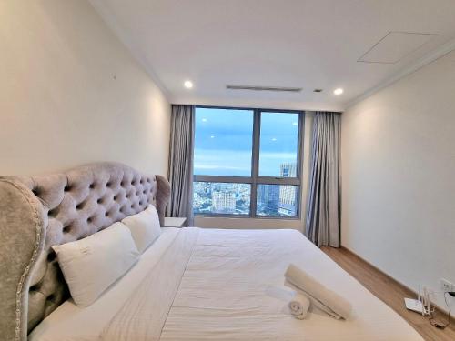 - une chambre avec un grand lit et une grande fenêtre dans l'établissement Happy Homes - Vinhomes Central Park, à Hô-Chi-Minh-Ville