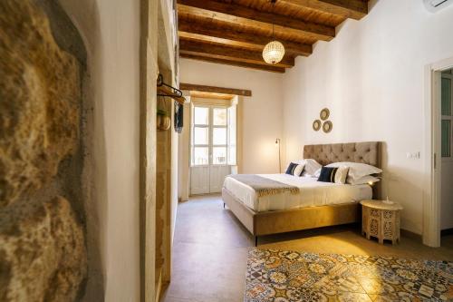 um quarto com uma cama e uma grande janela em Ortigia Boutique Palace em Siracusa