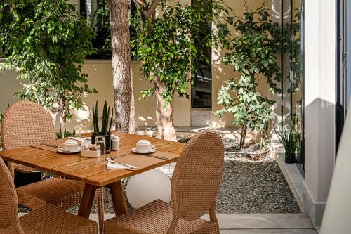 a wooden table and chairs on a patio with trees at Avra City Boutique Hotel in Chania