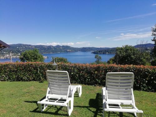 Dos sillas blancas sentadas en el césped con vistas al lago en B&B La Plesna, en Pella