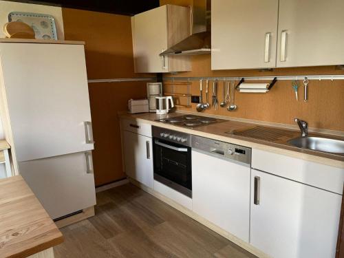 a small kitchen with white cabinets and a sink at Ferienpark Fedderwardersiel in Fedderwarderdeich