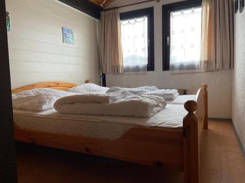 a bedroom with two beds with white sheets and two windows at Ferienpark Fedderwardersiel in Fedderwarderdeich