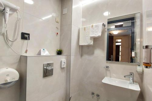 a white bathroom with a sink and a mirror at Hotel Siesta in Užice