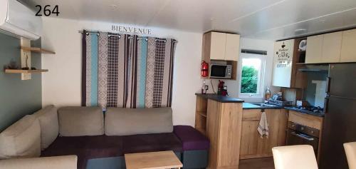 a small living room with a couch and a kitchen at davorel mobil home in Les Mathes