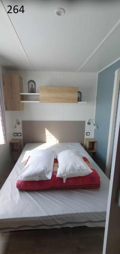 a bedroom with a large white bed with a red blanket at davorel mobil home in Les Mathes
