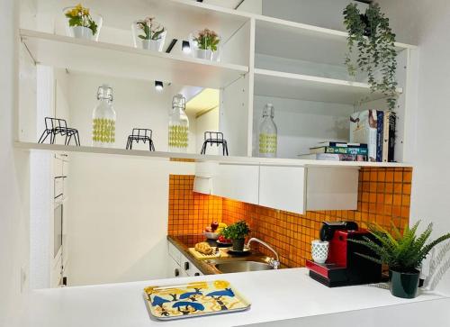 una cocina con estanterías blancas y fregadero en New, central studio with garden terrace and much privacy, en Zúrich