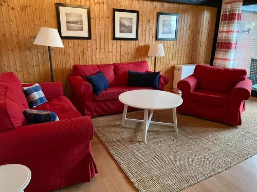 a living room with red couches and a table at Ferienpark Fedderwardersiel in Fedderwarderdeich