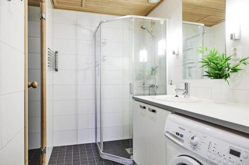 a white bathroom with a shower and a sink at Tasokas huoneisto kaupungin keskustassa. in Tampere