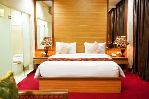 a bedroom with a large bed and two tables with lamps at Grand Buana Lestari Hotel in Duku