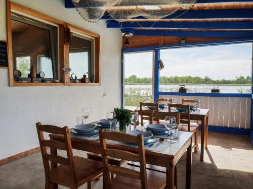 a dining room with tables and chairs and a large window at Hanul Casa Alba Fehér Ház Fogadó in Periprava