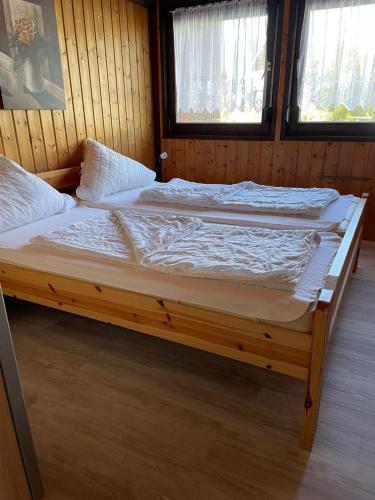 a large bed in a room with two windows at Ferienpark Fedderwardersiel in Fedderwarderdeich